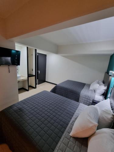 a hotel room with two beds and a flat screen tv at EMS Hoteles Centro Histórico in Veracruz