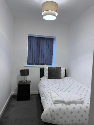 a bedroom with a white bed and a window at Amersham Park Apartment in Manchester