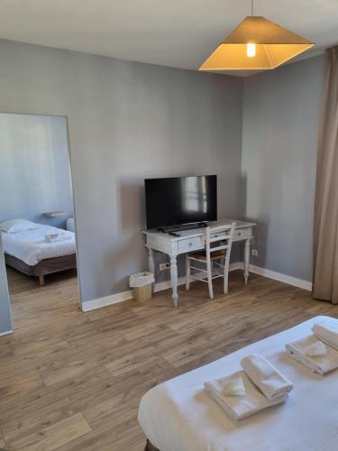 a room with two beds and a desk and a television at Hôtel-Restaurant Le Blueberry in Malaucène