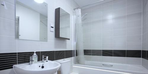 a bathroom with a sink and a toilet and a tub at Amersham Park Apartment in Manchester
