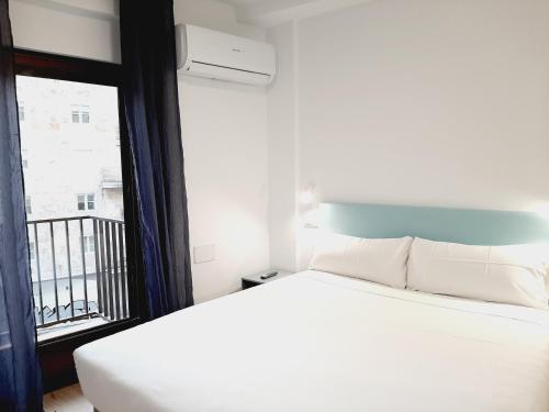 a bedroom with a white bed and a window at Hostal Carmen by gaiarooms in Salamanca