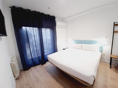 a bedroom with a large white bed and a window at Hostal Carmen by gaiarooms in Salamanca