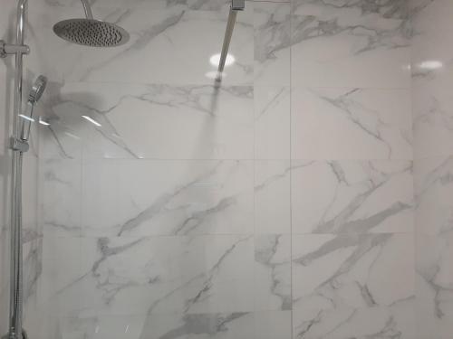 a white marble shower with a shower curtain at Hostal Carmen by gaiarooms in Salamanca