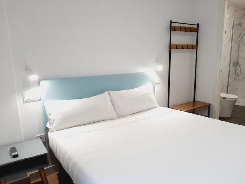 a bedroom with a white bed with a blue headboard at Hostal Carmen by gaiarooms in Salamanca