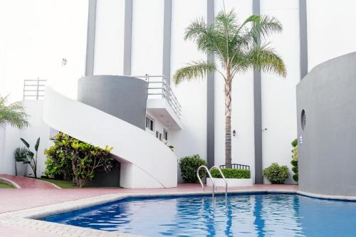- une piscine avec toboggan dans un bâtiment planté de palmiers dans l'établissement Hotel Mirage, à La Piedad Cavadas