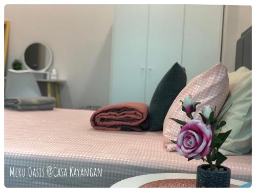 a bed with a pink mattress and a vase with flowers at Meru Oasis at Casa Kayangan Ipoh in Ipoh