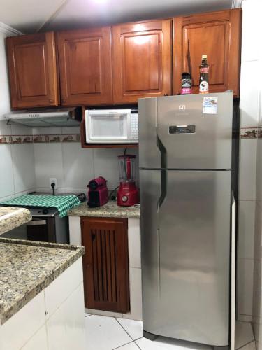 a stainless steel refrigerator in a kitchen with wooden cabinets at Flat lindo paraty in Paraty