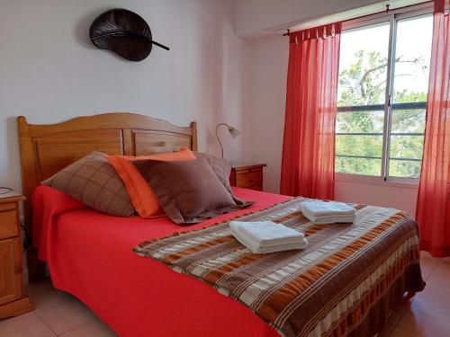 1 dormitorio con 1 cama roja y 2 toallas en Dpto. luminoso, céntrico, nuevo: LA SERENA en Tandil