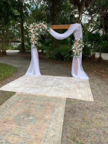 a wedding arch with flowers on top of a rug at Pirates Pointe Resort in Ruskin