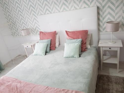 a bedroom with a large bed with pink and blue pillows at Apartamento Alagoinha by Umbral in Vila Nova de Milfontes