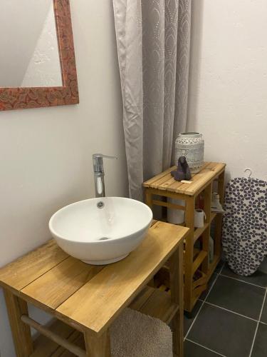 a bathroom with a white bowl sink on a wooden table at Adorable Gesthouse avec parking gratuit sur place. in Le Chêne