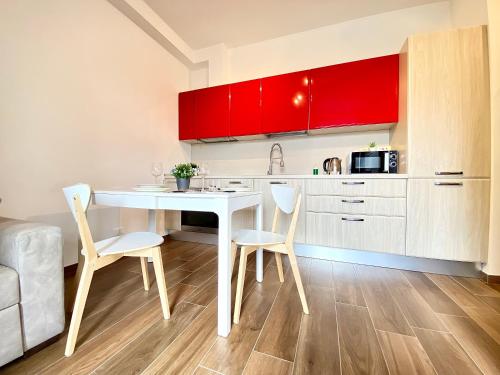 cocina con mesa blanca, sillas y armarios rojos en 15 minuti dall'Istituto Ortopedico Galeazzi - Appartamento Silenzioso con Cucina, WiFi e Netflix, en Milán