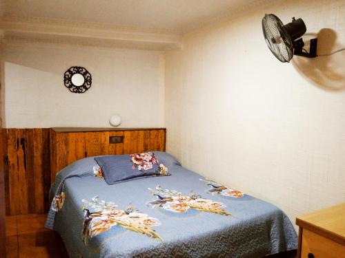 1 dormitorio con 1 cama con sábanas azules y reloj en la pared en Residencial la Cabaña, en Santiago