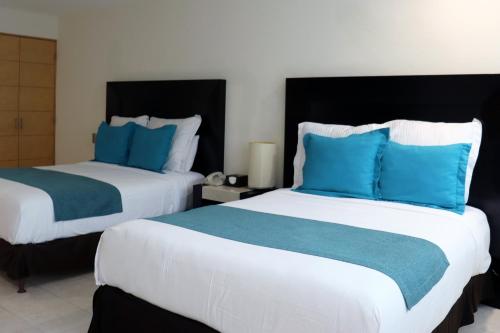 two beds in a hotel room with blue pillows at Hotel Rio 1300 in Cuernavaca