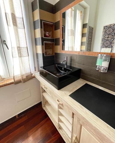 een badkamer met een zwarte wastafel en een spiegel bij Dolce Vita Suite Alghero in Alghero
