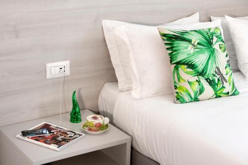 a bed with a green pineapple pillow and a table with a magazine at Piazza Tasso Max 1 in Sorrento