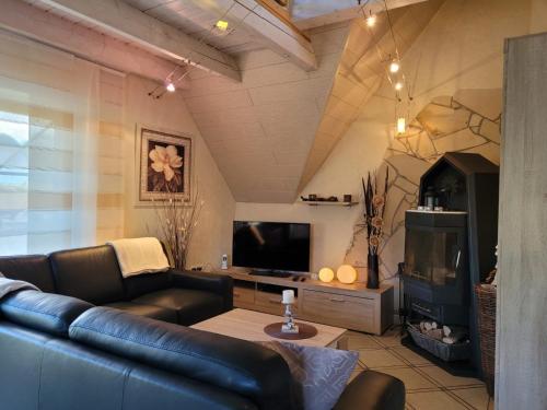 sala de estar con sofá de cuero y TV en Ferienwohnung Fitness Entspannung Sauna im Westerwald en Derschen