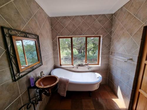 a bathroom with a tub and a sink and a window at Thabanyani Mabalingwe in Bela-Bela