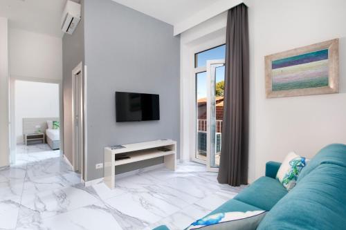 a living room with a blue couch and a tv at Piazza Tasso Max 1 in Sorrento