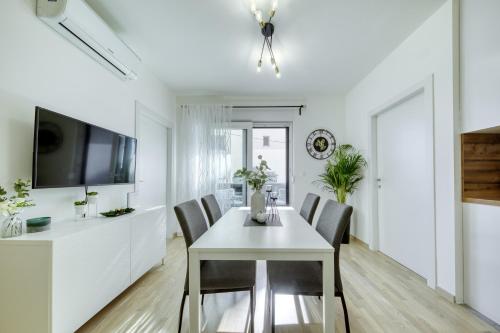 Una cocina y un comedor con una mesa y sillas blancas. en Apartment Alegria Zadar, en Zadar
