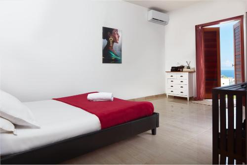 a bedroom with a bed with a red blanket at Savane Paille in Deshaies