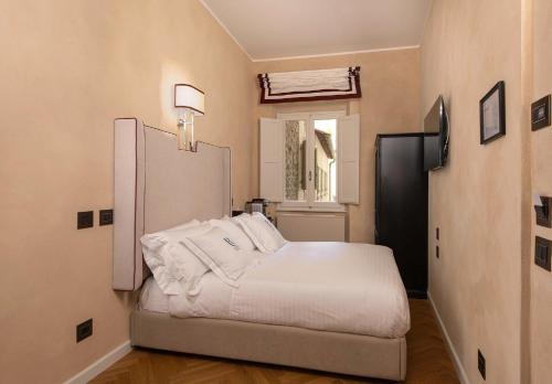 a bedroom with a bed with white sheets and a window at Relais Uffizi in Florence