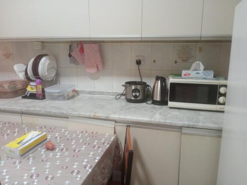 a kitchen counter with a microwave and a table at Transient furnished. Room just 1 min to Al ain mall in Al 'Ayn