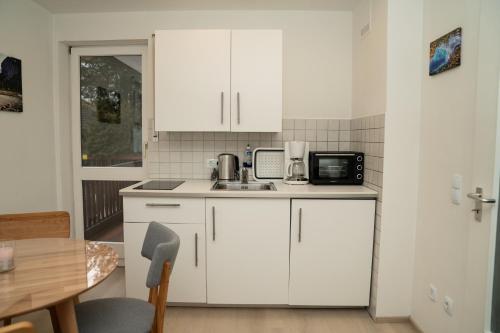 a kitchen with white cabinets and a sink and a table at FeWo Waldi am Kurpark in Bad Tölz
