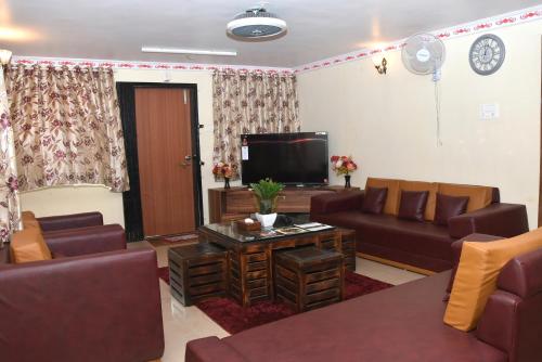 a living room with couches and a flat screen tv at Quinte Hills Residency in Panchgani