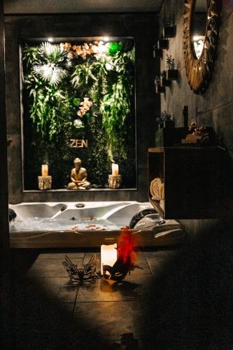 a bathroom with a bath tub with candles and a large window at Loveroom intimiste et haut de gamme à 30 min de Toulouse in Lagrâce-Dieu