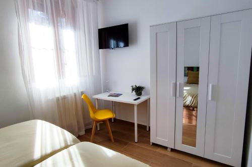 a bedroom with a bed and a desk with a yellow chair at LOFT de Tita Larrea in Arriondas