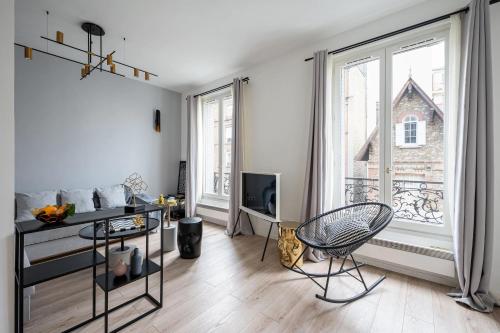 ein Wohnzimmer mit einem Stuhl und einem großen Fenster in der Unterkunft Appartement Design&Nouveau, ParisExpo Pte-de-Versaille, Parking&Netflix in Issy-les-Moulineaux