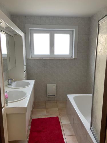 uma casa de banho com 2 lavatórios, uma banheira e uma janela em Ruim zonnig appartement op 50m van strand em Ostend
