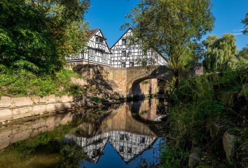 a building on a bridge over a river at Neumühle Resort & Spa in Hammelburg