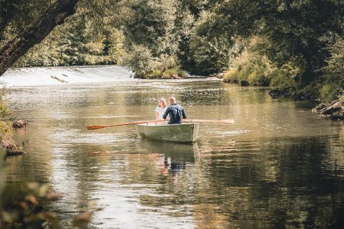 a man and woman in a row boat on a river at Neumühle Resort & Spa in Hammelburg