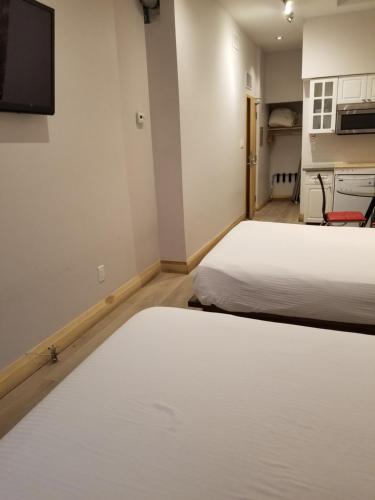 a bedroom with two beds and a tv on the wall at Dragon Gate Inn in Toronto