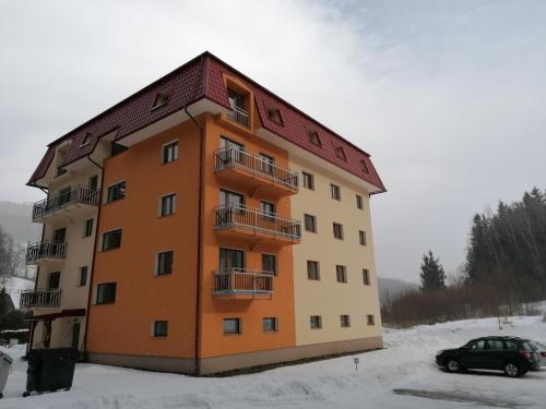 an apartment building in the snow with a car in front at Apartmán 68 Horní Lipová in Lipova Lazne