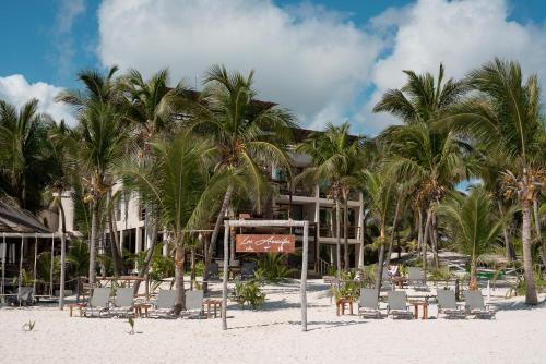 a beach with chairs and palm trees and a building at Los Arrecifes in Tulum
