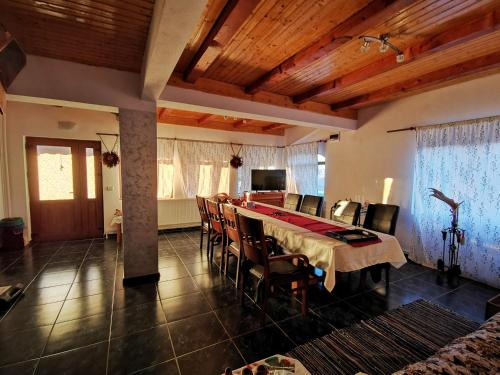 a dining room with a long table and chairs at Jugul Țăranului Agropensiune Polovragi, Gorj in Polovragi