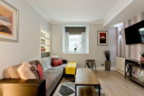 a living room with a couch and a table at Ultra Modern, West End Village, Refurbished basement appt in Edinburgh