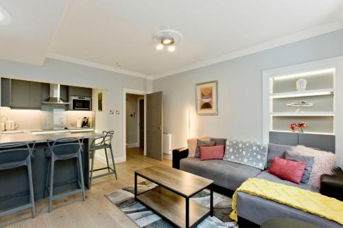 a living room with a couch and a kitchen at Ultra Modern, West End Village, Refurbished basement appt in Edinburgh