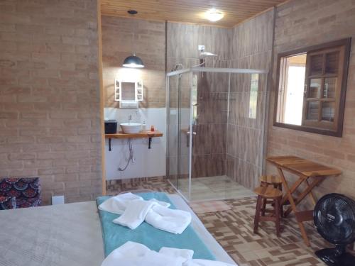 baño con ducha y mesa con toallas en Chalés Bons Ventos - Chalé Estrela en São Bento do Sapucaí
