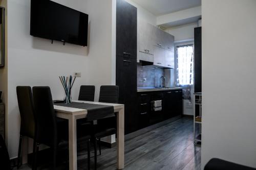 a kitchen with a table with chairs and a television on the wall at L’Archè Lodovico il Moro – House on the Navigli River in Milan