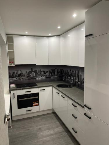 una cocina con armarios blancos y fregadero en Elite Apartments, en Rēzekne