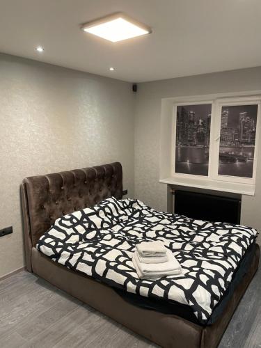a bedroom with a bed with a black and white comforter at Elite Apartments in Rēzekne