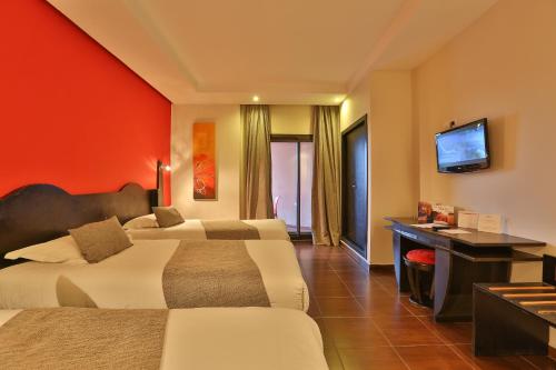 a hotel room with two beds and a desk and a television at Red Hotel Marrakech in Marrakesh