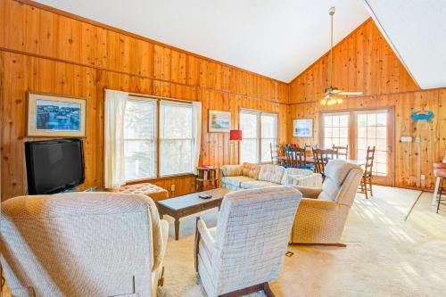 a living room with wooden walls and furniture and a tv at The Owen-ly Place to Be in Holden Beach