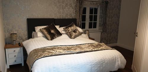 1 dormitorio con 1 cama grande con sábanas y almohadas blancas en Bell Inn en Evesham