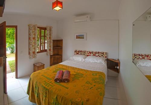 um quarto com uma cama grande e um cobertor amarelo em Pousada Do Sol Garopaba em Garopaba