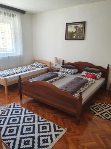 two beds in a room with wooden floors at Diamond M Apartment in Bihać